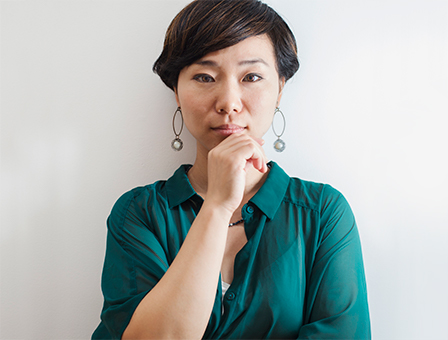Asian woman in her 30's with green shirt holding her chin